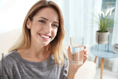 Young woman holding glass with clean water at home