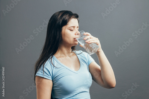 Portrait of beautiful woman drinking water isolated on gray background