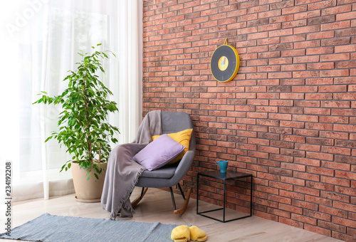 Stylish room interior with armchair and potted ficus