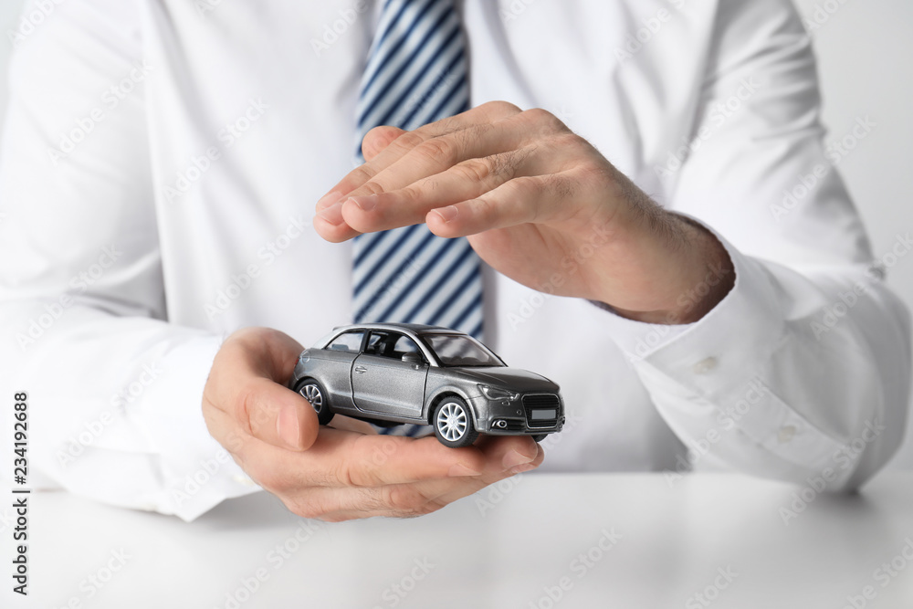 Male insurance agent holding toy car, closeup Male insurance agent holding toy car, closeup