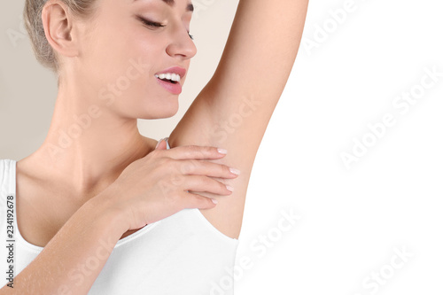 Young woman showing armpit on color background, space for text. Using deodorant