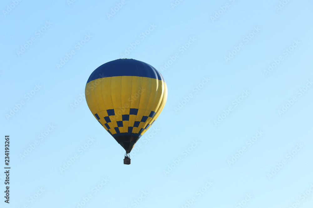 Fototapeta premium Colorful hot air balloon flying in blue sky. Space for text
