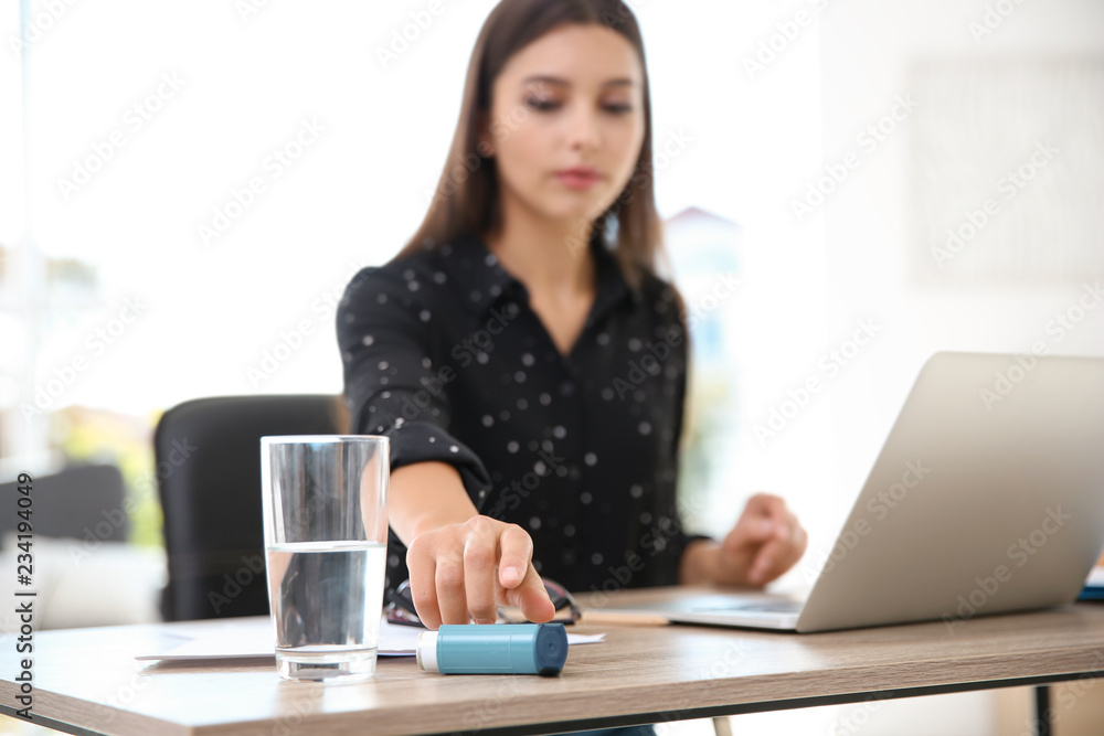 Woman with asthma inhaler at table in light room Woman with asthma inhaler at table in light room