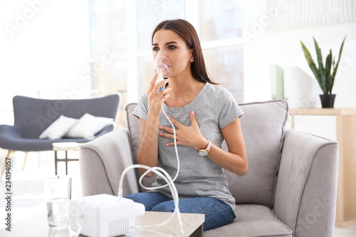 Foto Young woman with asthma machine in light room