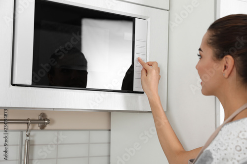 Young woman using microwave oven at home