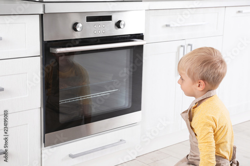Little boy baking something in oven at home