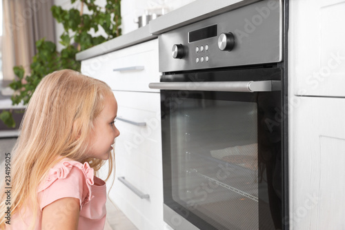 Little girl baking something in oven at home