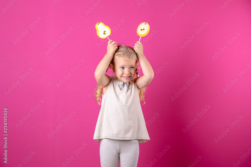 Cute little girl with candies on color background