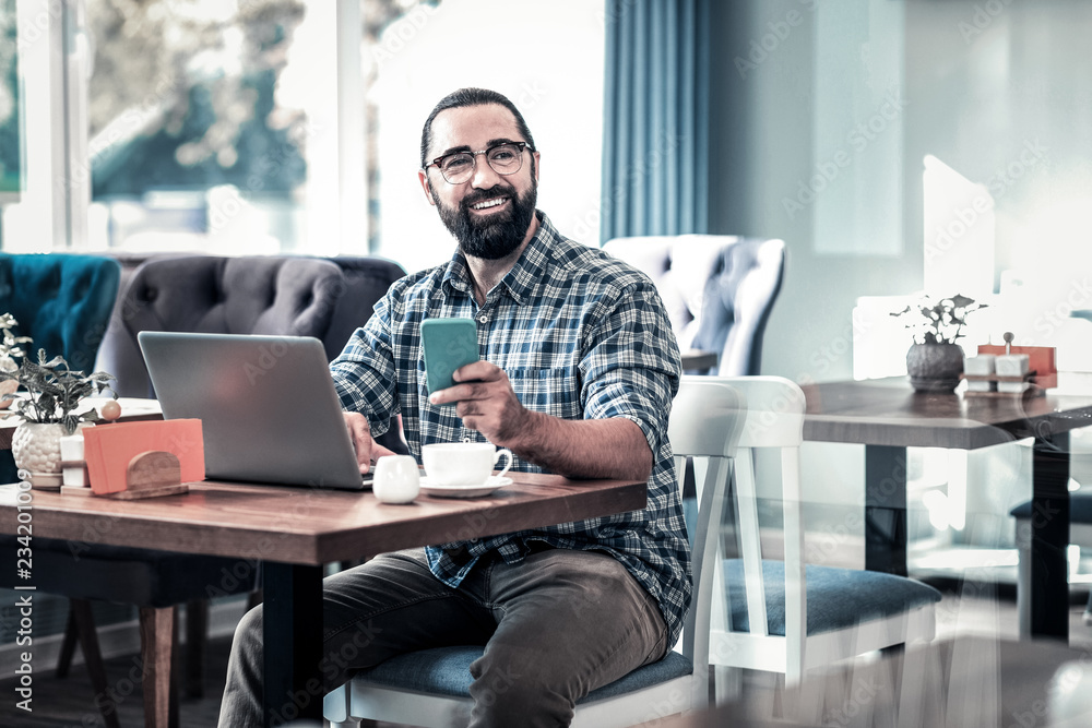 Work remotely. Successful businessman wearing squared shirt working remotely sitting in restaurant Work remotely. Successful businessman wearing squared shirt working remotely sitting in restaurant