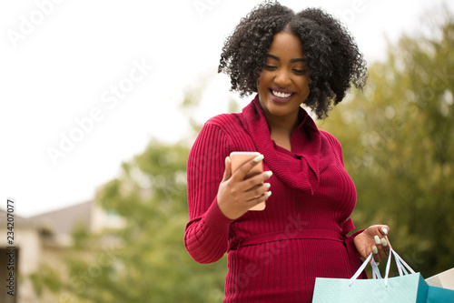 Beautiful African American woman shopping and texting. © digitalskillet1