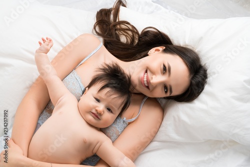 Happy mother in bed with baby boy high angle shot