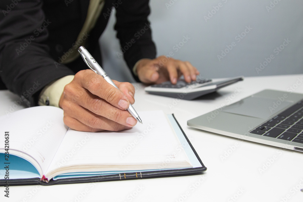 businessman using calculator and holding money for calculate tax in office. businessman using calculator and holding money for calculate tax in office.
