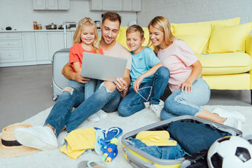 happy family using laptop, planning summer vacation, packing luggage and having great time, travel concept