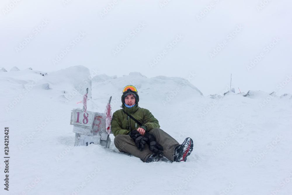 The young man rests on a halt after climbing to the top of the mountain The young man rests on a halt after climbing to the top of the mountain