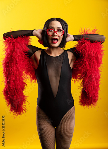 Fun, colorful portrait of pretty Asian woman wearing red feather boa and heart shaped glasses