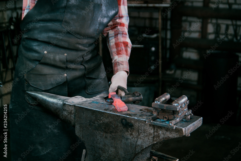Blacksmith working with red hot metal workpiece of new hammer at anvil in a forge Blacksmith working with red hot metal workpiece of new hammer at anvil in a forge