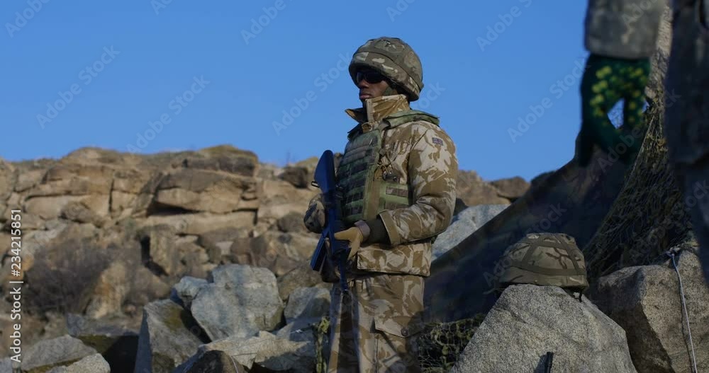 Medium shot of fully equipped and armed african american soldier looking around during a mission Medium shot of fully equipped and armed african american soldier looking around during a mission