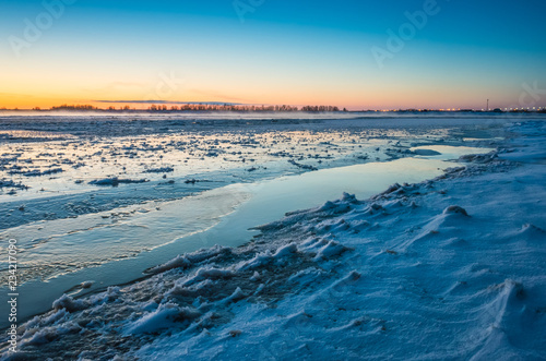 Winter landscape with sunset. Most of the frame takes a snowy field.