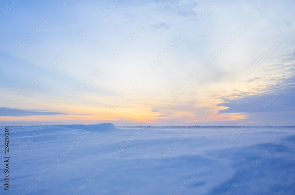 Winter landscape with sunset. Most of the frame takes a snowy field.