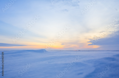 Winter landscape with sunset. Most of the frame takes a snowy field.