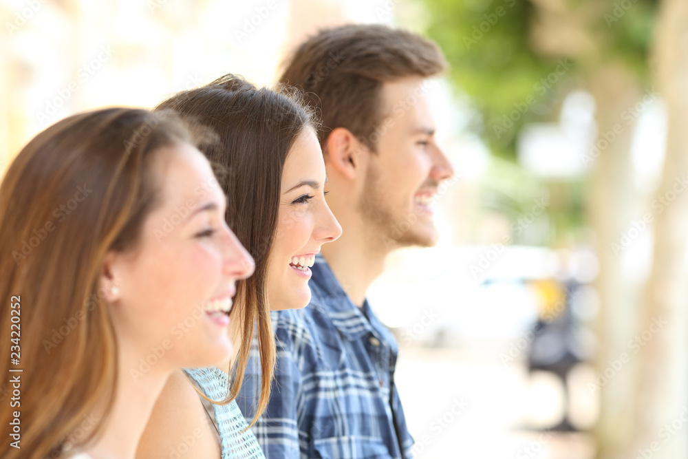 Profile of three friends looking away in the street Profile of three friends looking away in the street