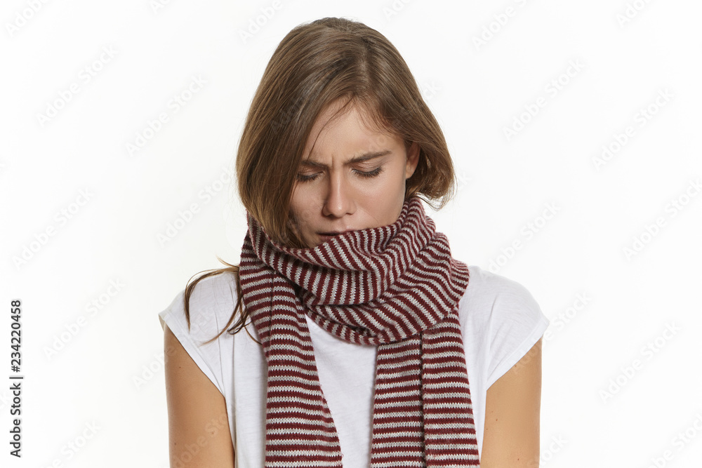 Frustrated young woman having sore throat posing in studio wearing warm  scarf around her neck. Picture of upset Caucasian girl suffering from  influenza, wrapped in knitted scarf, being unhappy Stock Photo