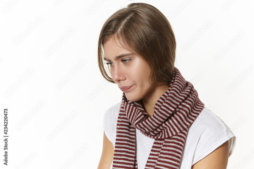 Isolated view of upset unhappy young woman wrapped in knitted scarf suffering from sore throat spending day at home, feeling depressed. Sick sad girl having high temperature because of flu Isolated view of upset unhappy young woman wrapped in knitted scarf suffering from sore throat spending day at home, feeling depressed. Sick sad girl having high temperature because of flu