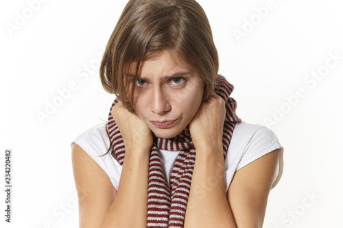 Disease, health condition, sickness and illness concept. Close up image of sad girl with sore throat posing in studio. Depressed young woman with painful expression, having influenza symptoms