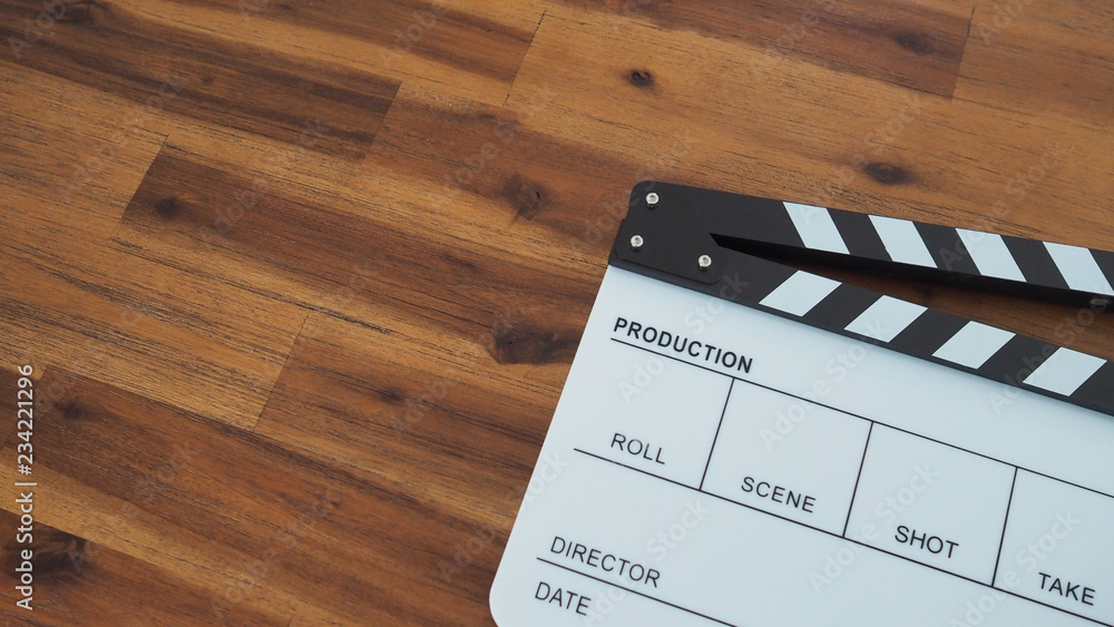 Clapper board or movie slate use in video production, film and cinema industry. It's white color on wood background.