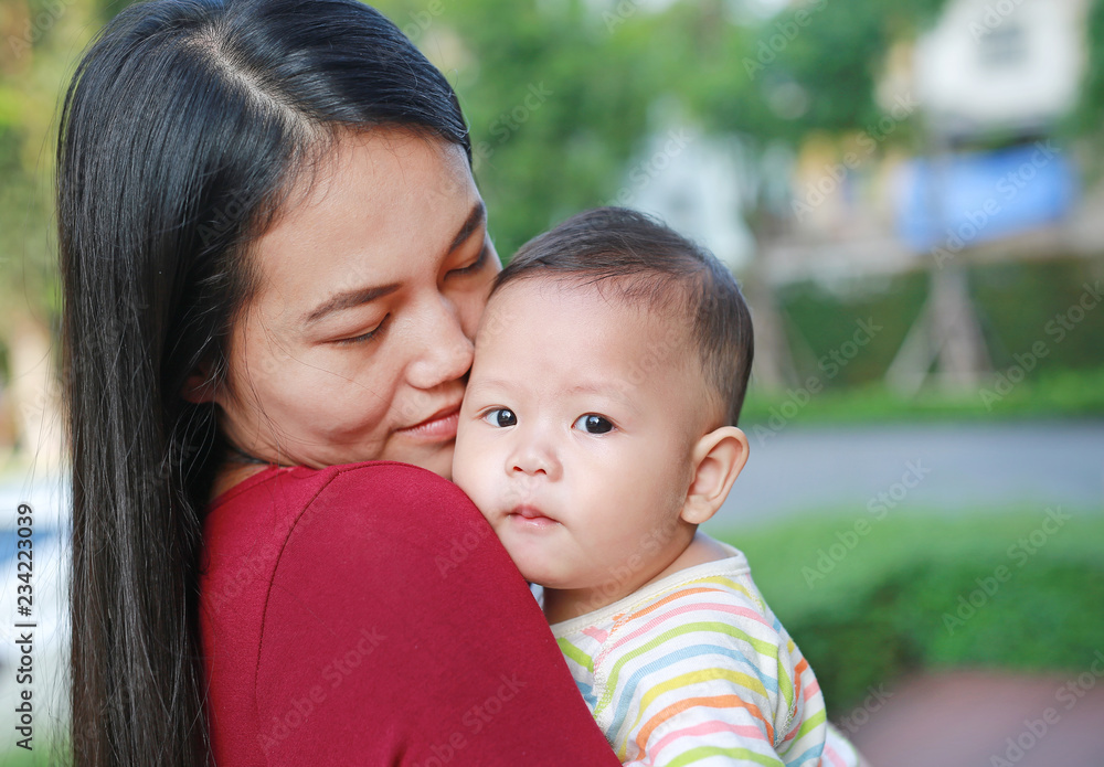 Portrait of Asian mother carrying and kissing her infant baby boy outdoor. Portrait of Asian mother carrying and kissing her infant baby boy outdoor.