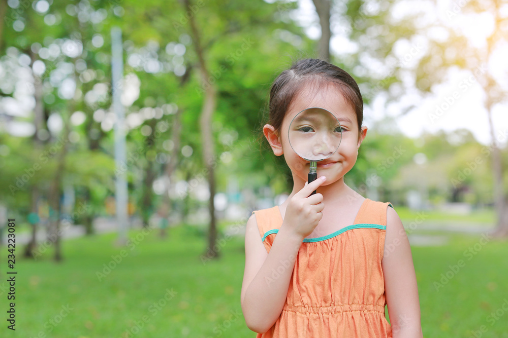Portrait little Asian child girl looking through magnifying glass on park garden. Portrait little Asian child girl looking through magnifying glass on park garden.