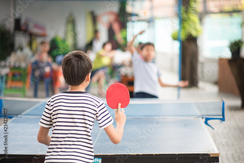 Kid playing table tennis outdoor with family