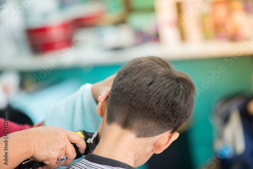 Little boy sitting for hair cut at barber shop