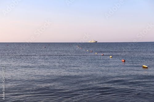 Background. Blue sea, pink sky at dawn and a white ship on the horizon. Cropped shot, perspective, place for text. Concept of rest, vacation, weekend and cruise.