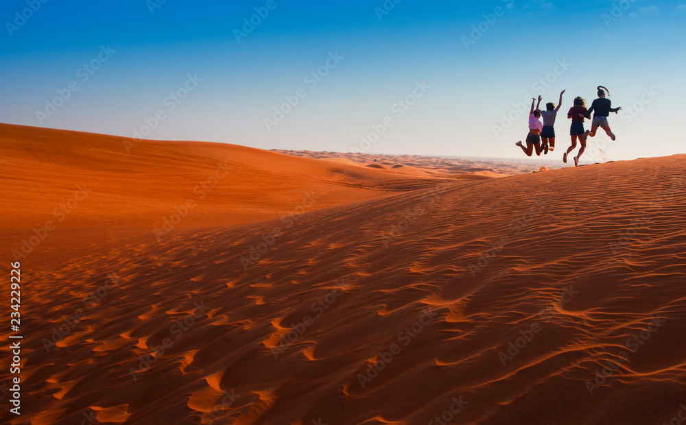 Obraz premium happy people jumping in the desert sunset landscape. travel concept