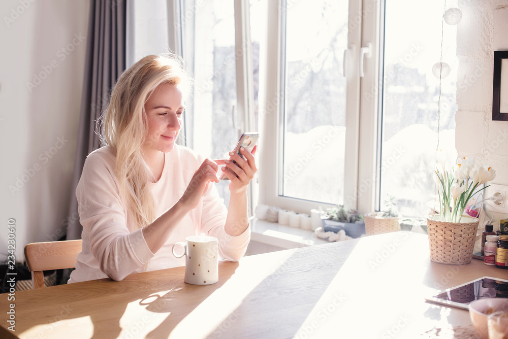 Thoughtful young woman in bathrobe eating breakfast in kitchen
