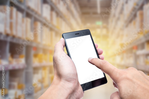 hand using smartphone with warehouse inventory management technology concept background.