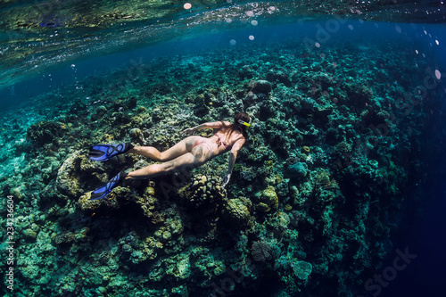 Young woman free diver explores reef in ocean, underwater photo with diver
