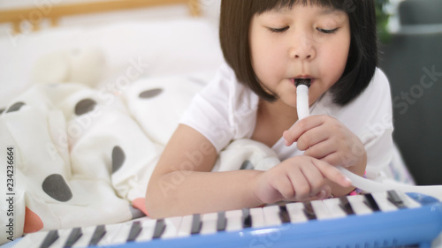 Happy little Asian girl playing melodica blow organ photo