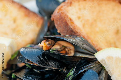  black mussels with crispy bread on a plate photo