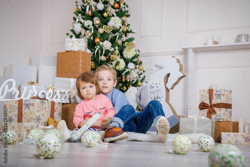 Boy and girl in the studio with a Christmas interior. Little Brother and Sister at Christmas. Waiting for children to give presents
Boy and girl in the studio with a Christmas interior. Little Brother and Sister at Christmas. Waiting for children to give presents