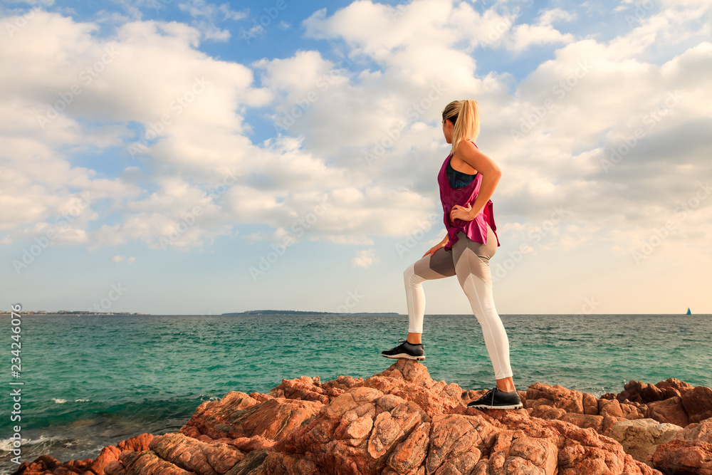 Attractive sporty blonde woman looking at the horizon at the sea Attractive sporty blonde woman looking at the horizon at the sea