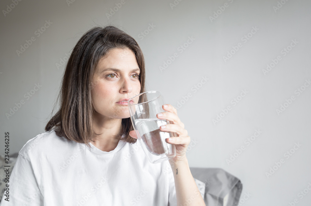 Beautiful charming woman drinking a big glass of water and wearing white clothes Beautiful charming woman drinking a big glass of water and wearing white clothes