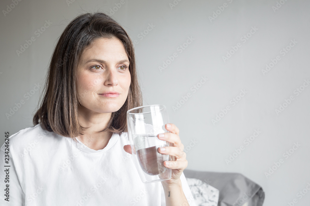 Beautiful charming woman drinking a big glass of water and wearing white clothes Beautiful charming woman drinking a big glass of water and wearing white clothes