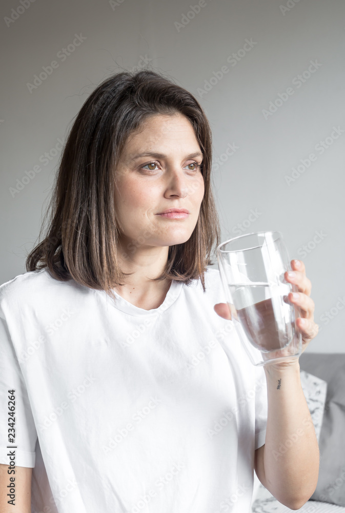 Beautiful charming woman drinking a big glass of water and wearing white clothes Beautiful charming woman drinking a big glass of water and wearing white clothes