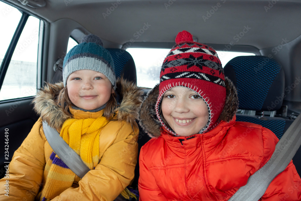 Happy children in the car in the back seat winter trip