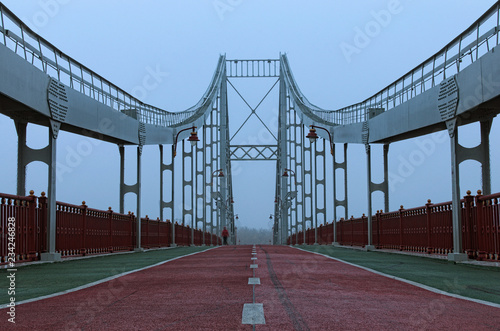 Foggy landscape view of Pedestrian Bridge across the Dnipro River to the Trukhaniv island. The concept of foggy weather in the city. Kyiv, Ukraine