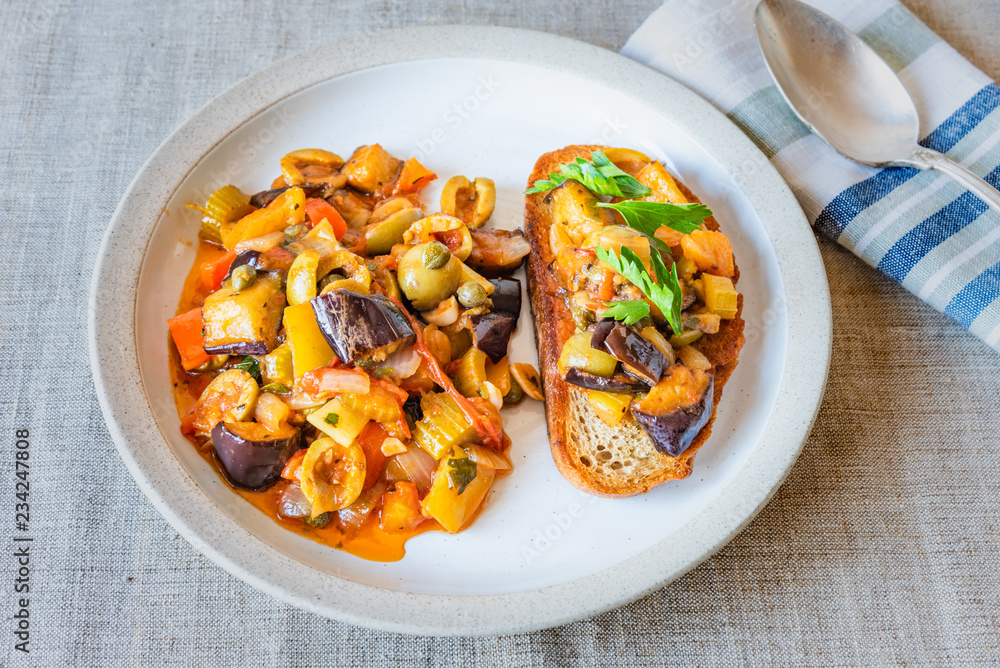 Caponata siciliana on a plate with toast close-up, top view Caponata siciliana on a plate with toast close-up, top view