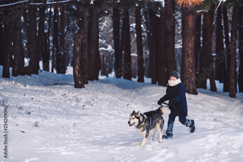 dog and boy run in the winter in the forest. The concept of active holiday in the winter holidays