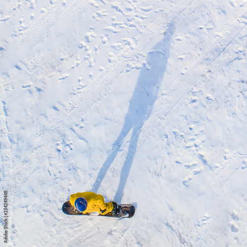 Snowboarder in yellow clothes with shadow in yellow  aerial view